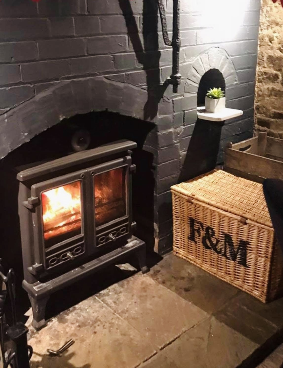 Cast-iron wood-burning stove aglow beside a wicker hamper